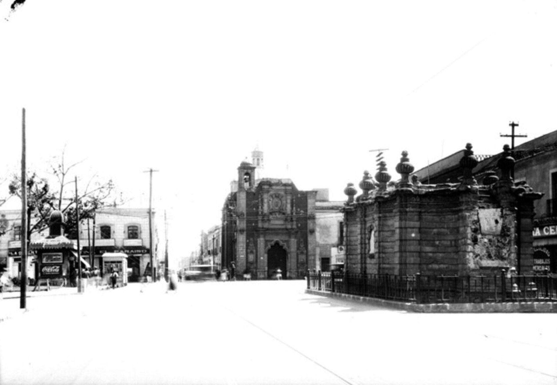 Alt text: Historic street view with old buildings, archway, and cross.