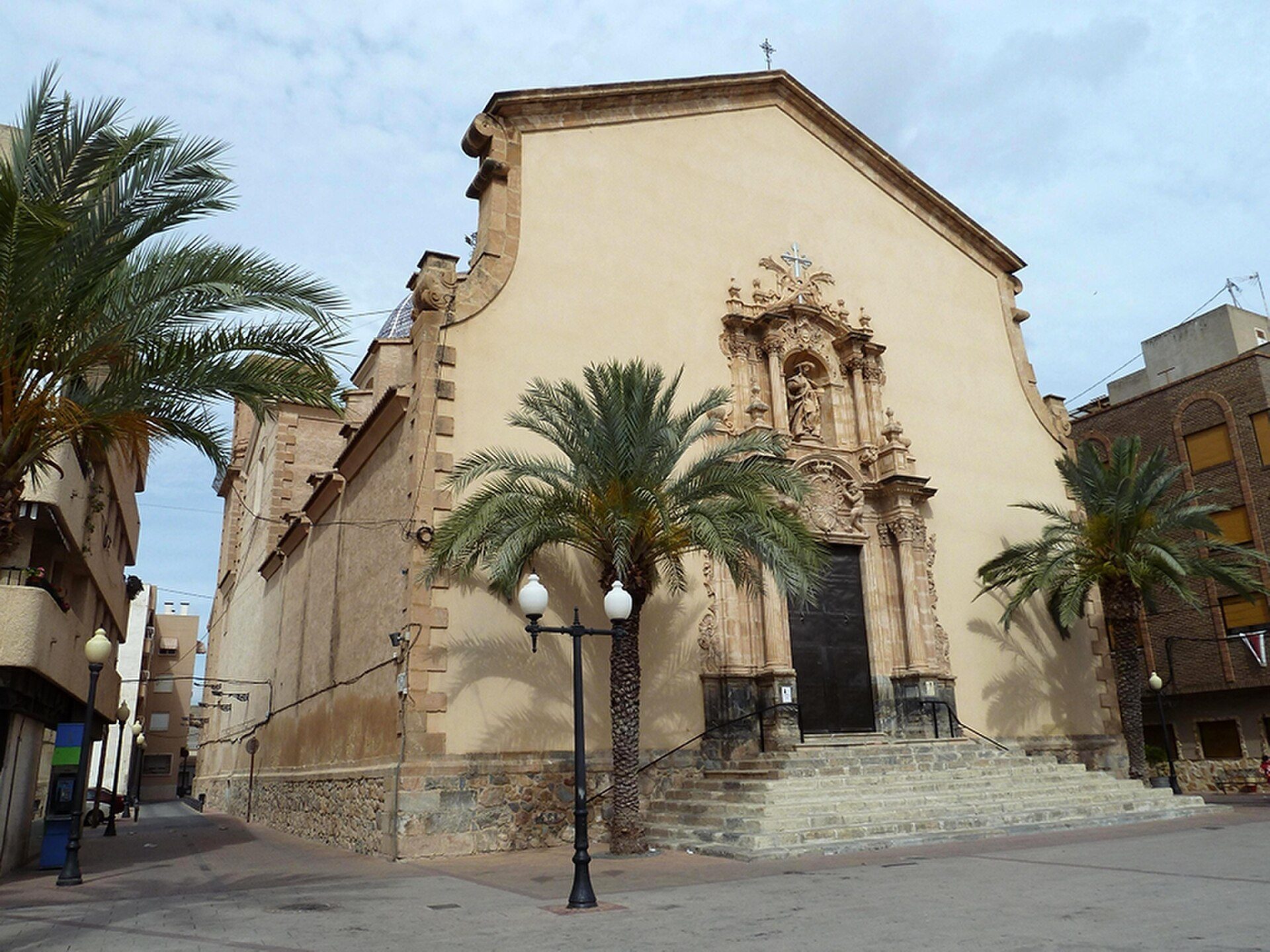 Alt text: Historic church with palm trees, stone facade, and ornate entrance.