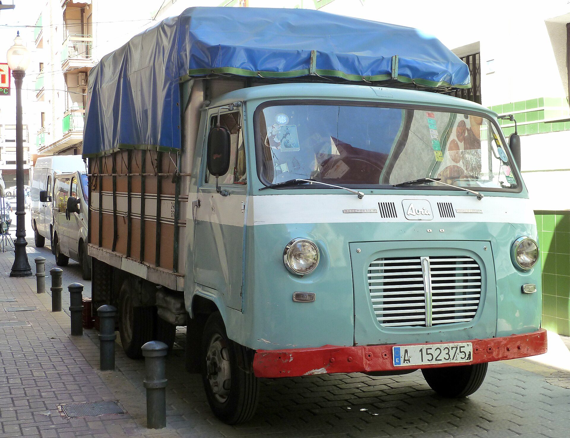 A vintage blue and white delivery truck parked on a city street.