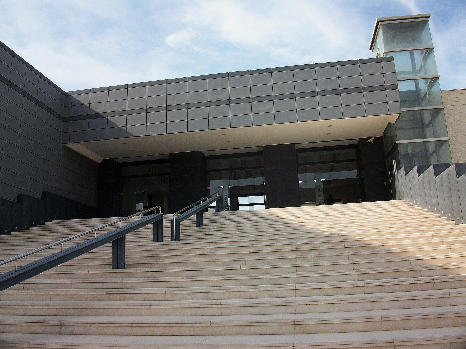 Modern building with large glass windows and wooden steps.