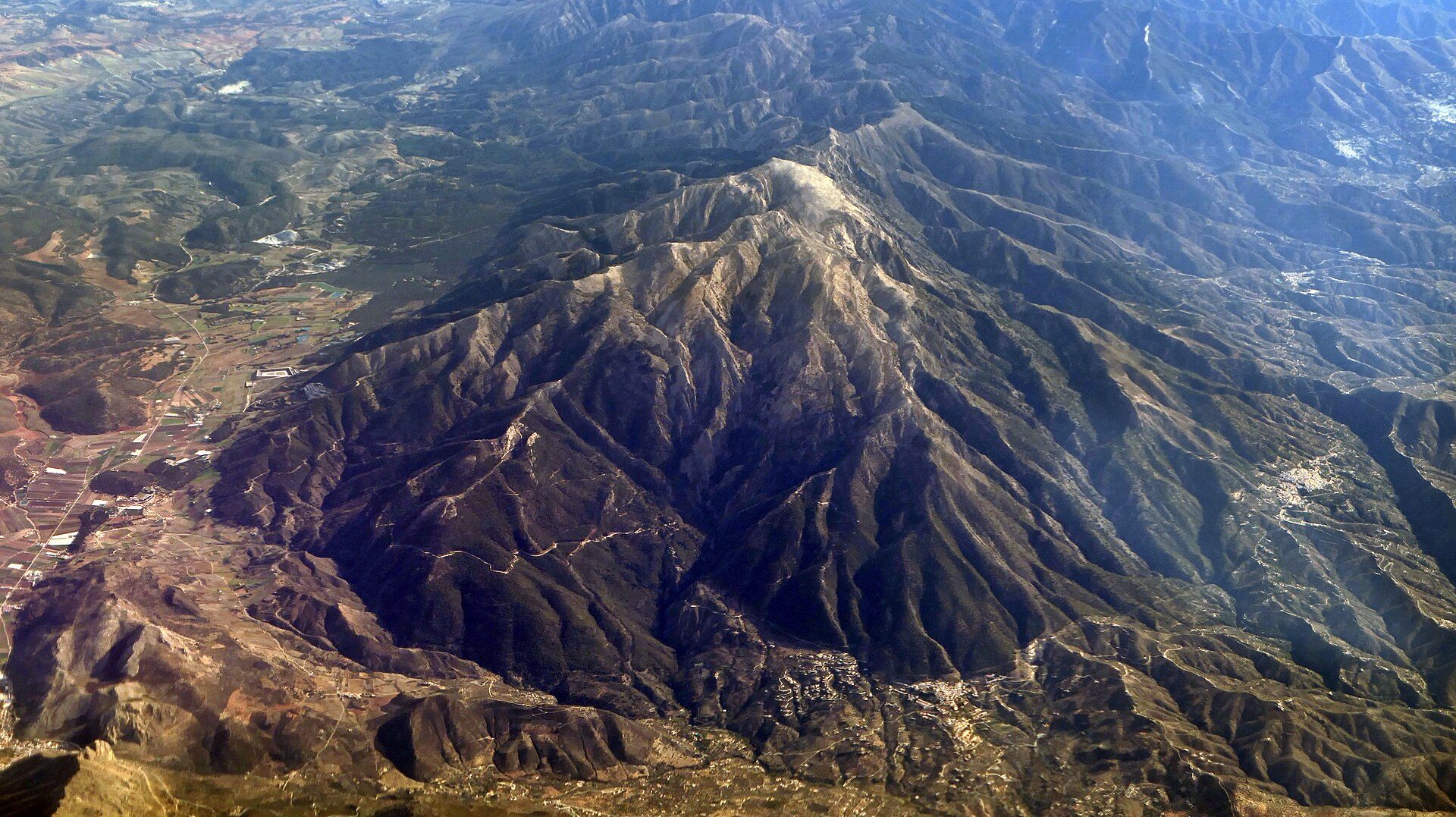 Aerial view of a mountainous landscape with a prominent peak and surrounding valleys.