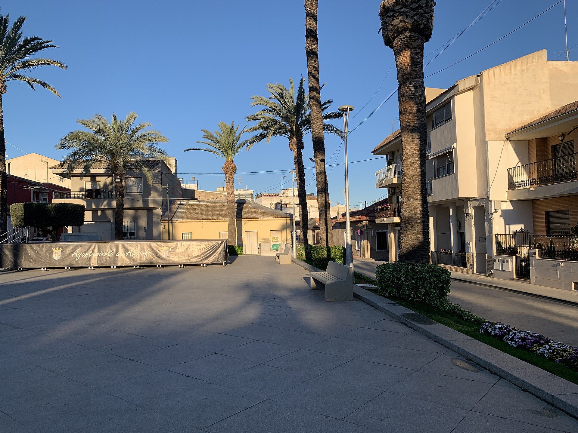 A spacious living room with a balcony, offering a view of palm trees and a clear blue sky.