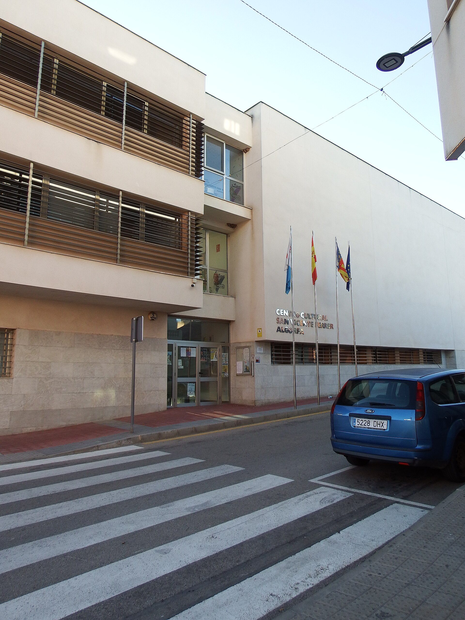 Modern building with flags, large windows, and a pedestrian crossing.