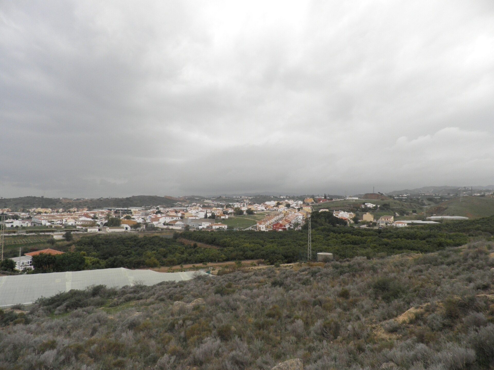 Alt text: Spacious living room with panoramic view of a quaint town and rolling hills.