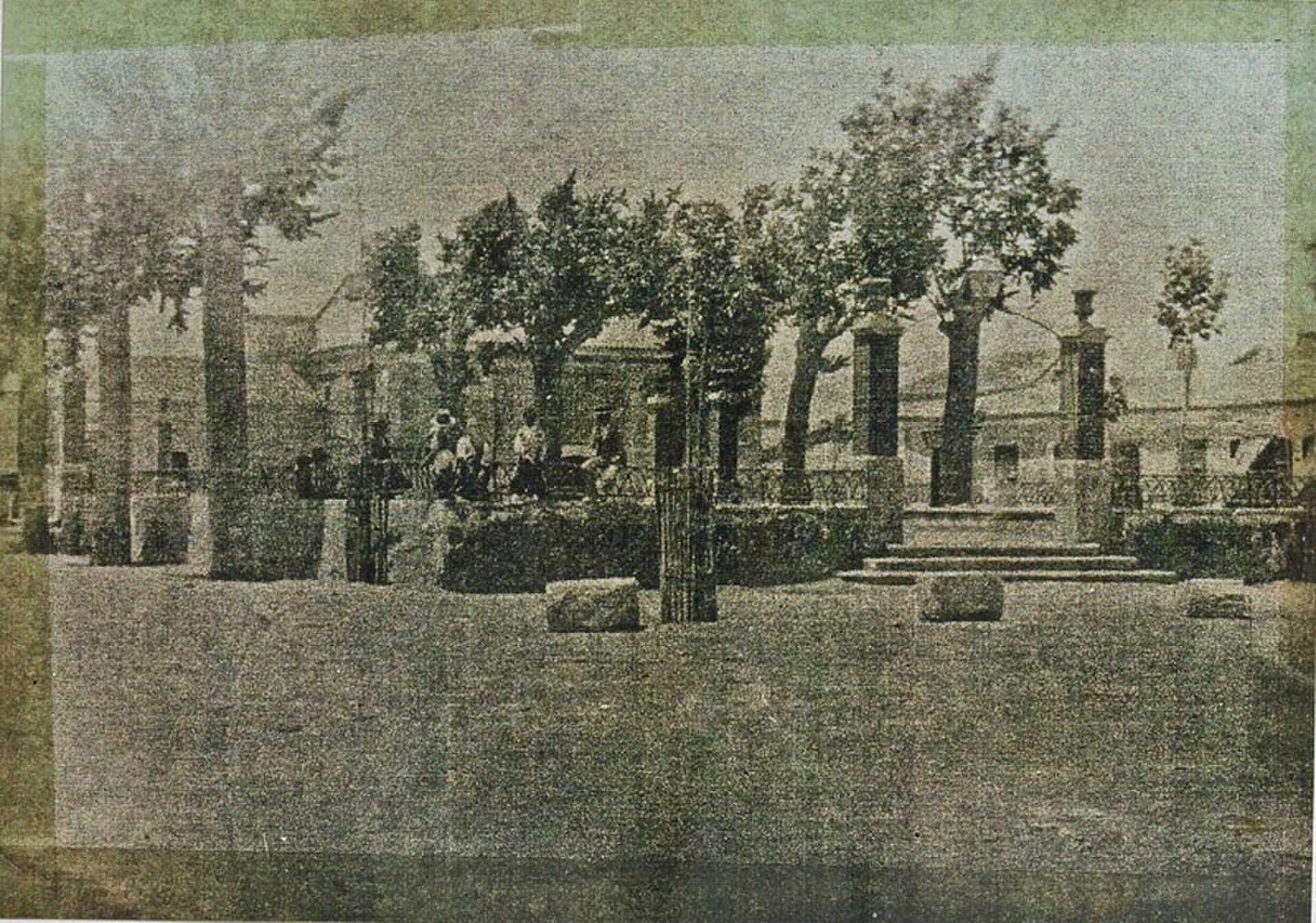 Historic garden with classical columns, trees, and people relaxing.