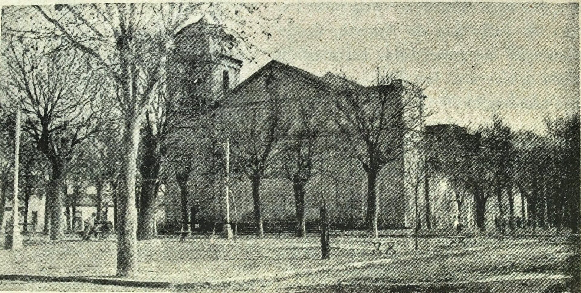 Alt text: Black and white photo of a large church with tall trees and a park view.