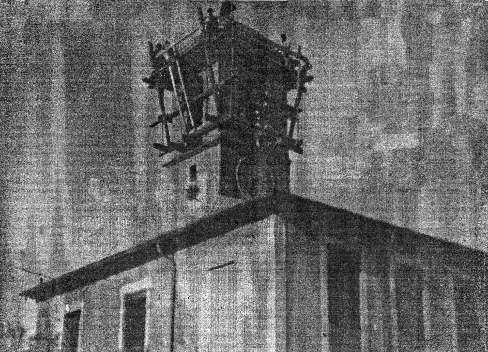 Alt text: Black and white photo of a clock tower with a bell structure on top.