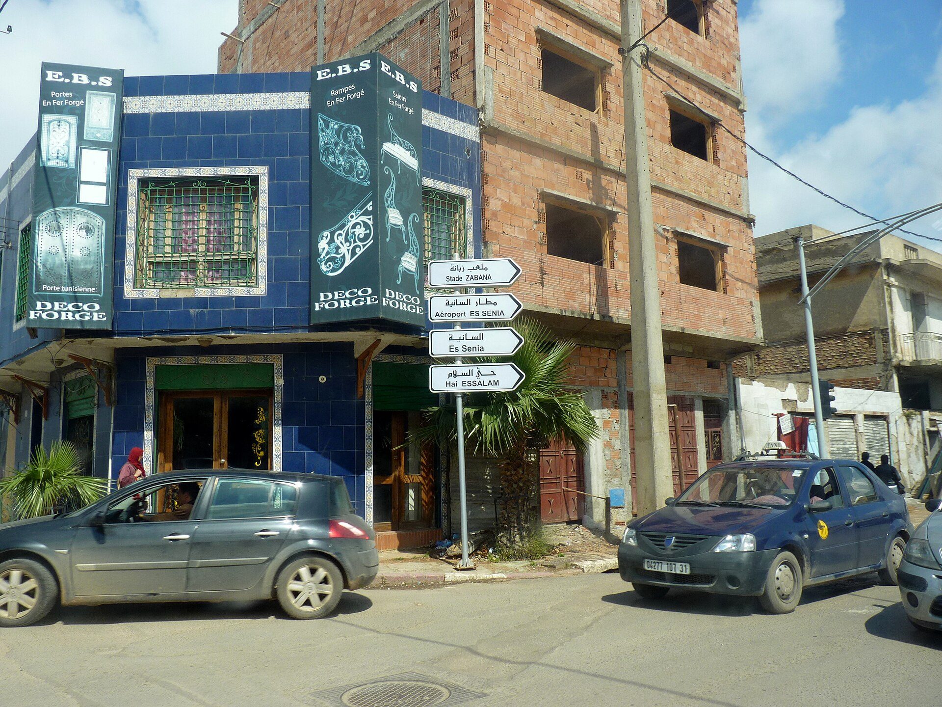 A blue building with a sign for "E.B.S. Deco Palace" and a street view with cars.