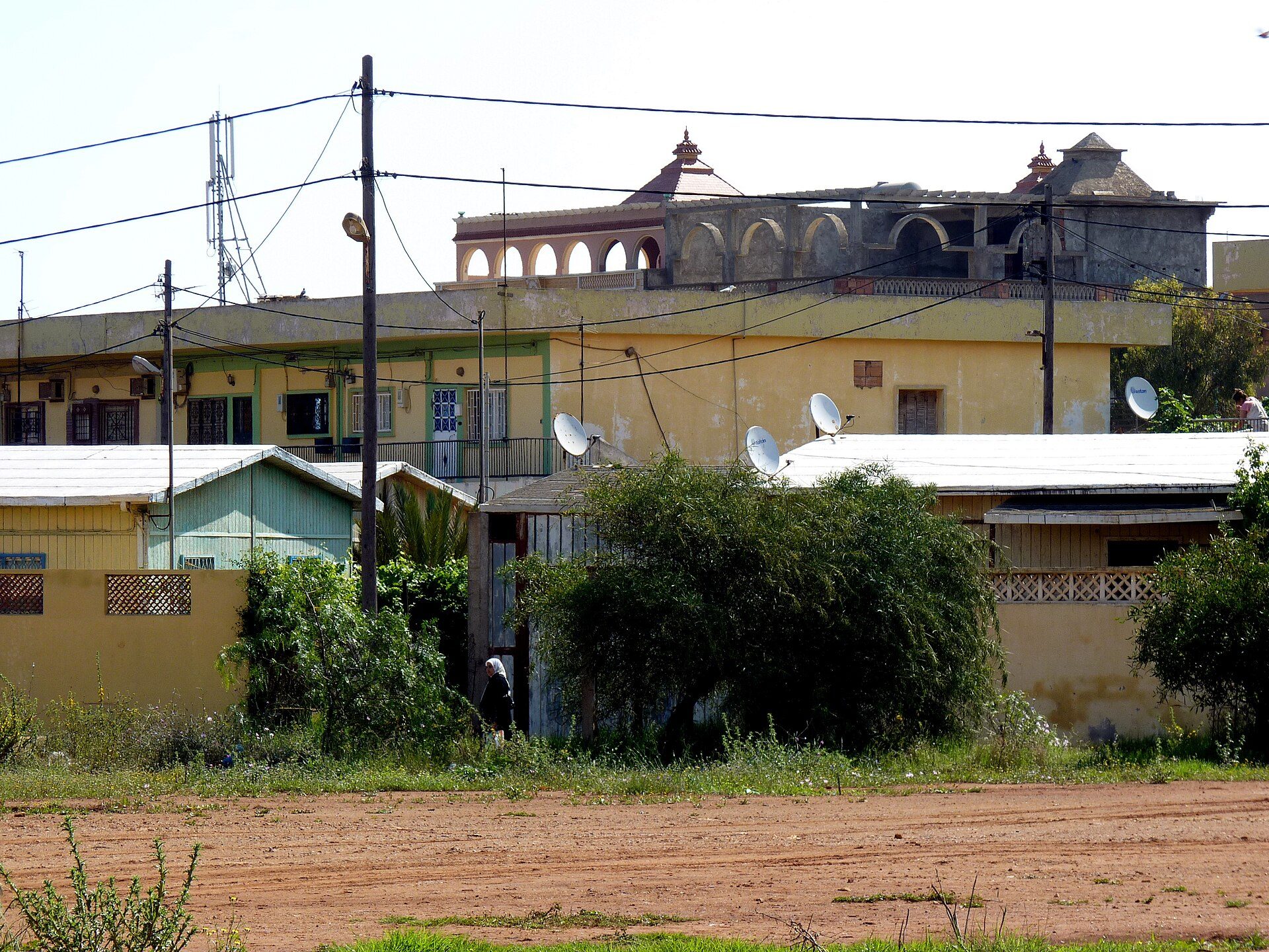 Traditional house with multiple rooms, satellite dishes, and a view of a large building.
