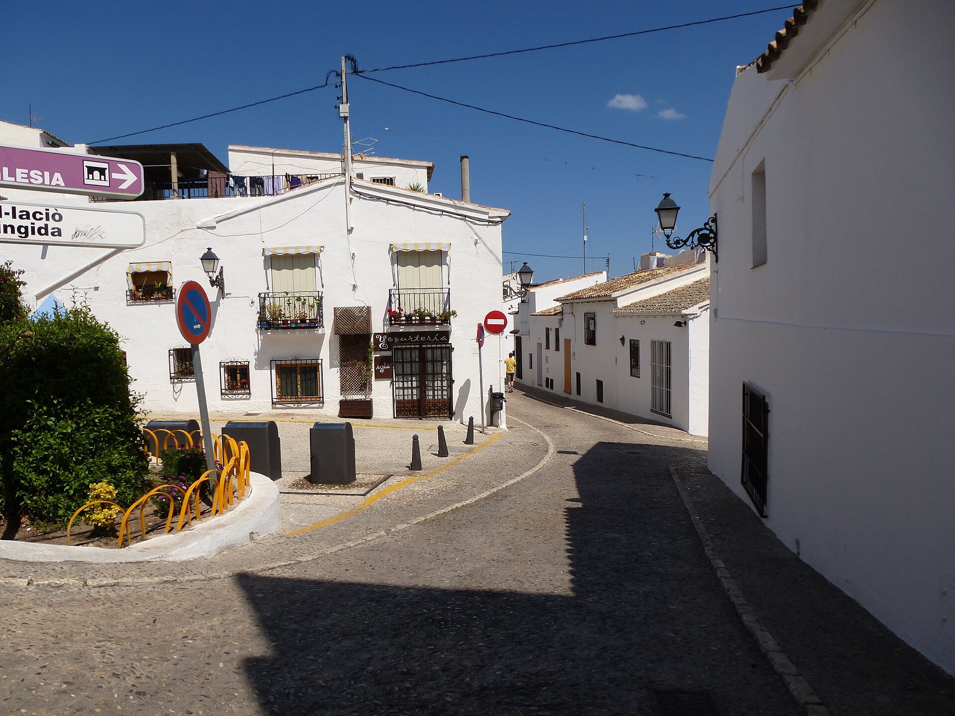 A cozy white-walled room with a balcony, offering a charming street view.
