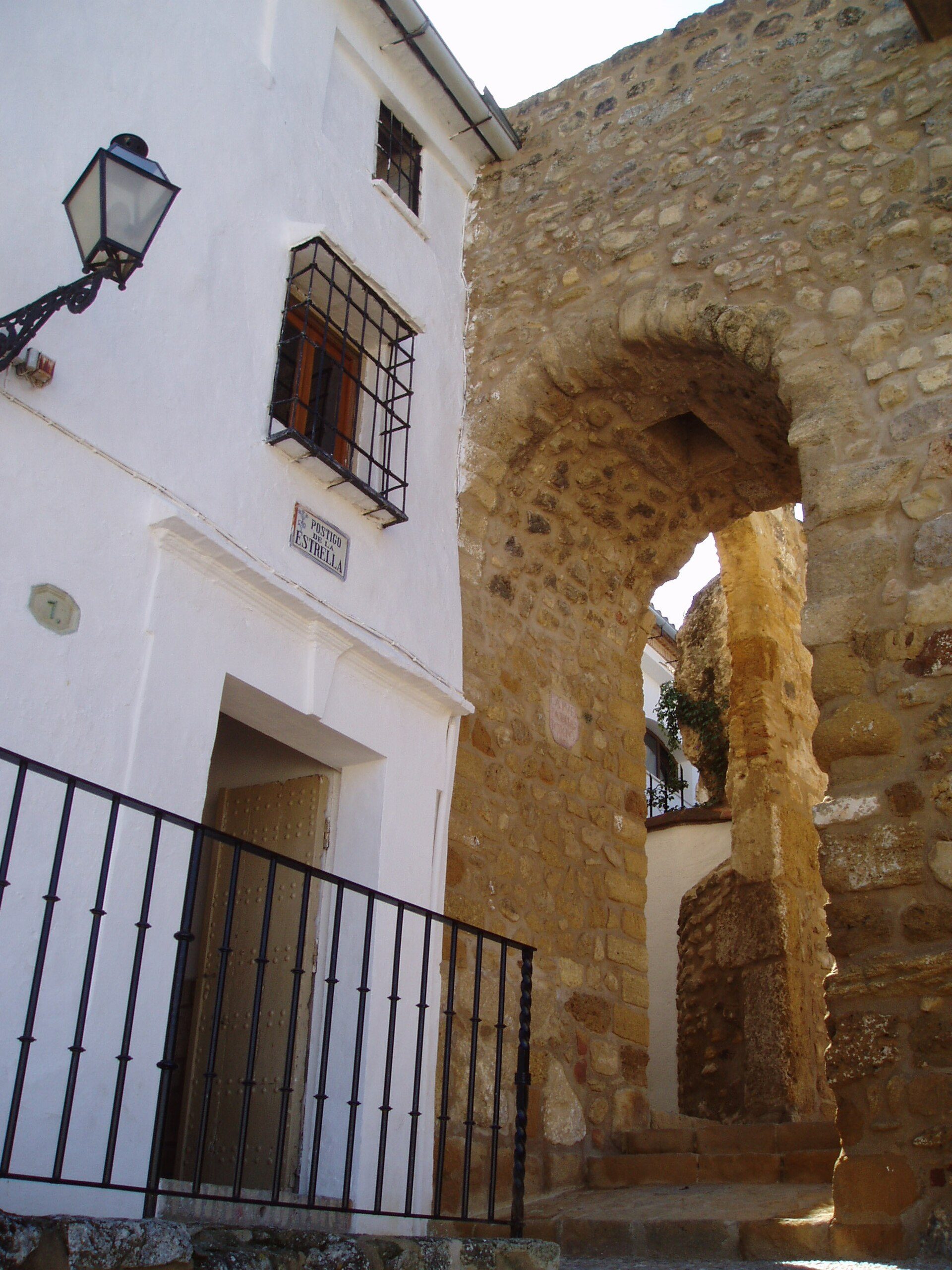 Traditional white-walled room with arched stone doorway, featuring a small window and black metal railing.