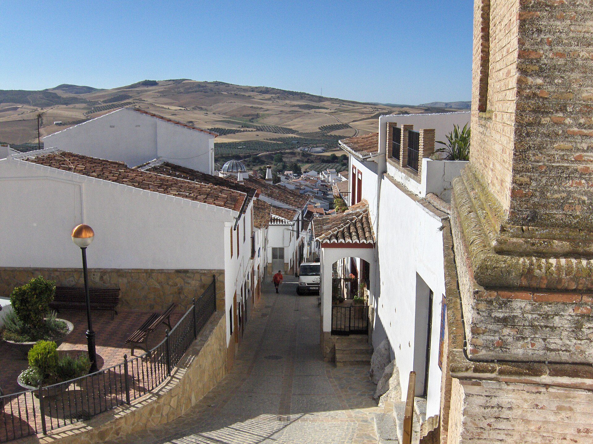 Traditional white-walled room with terracotta roof, scenic mountain view, stone patio, and street lamp.