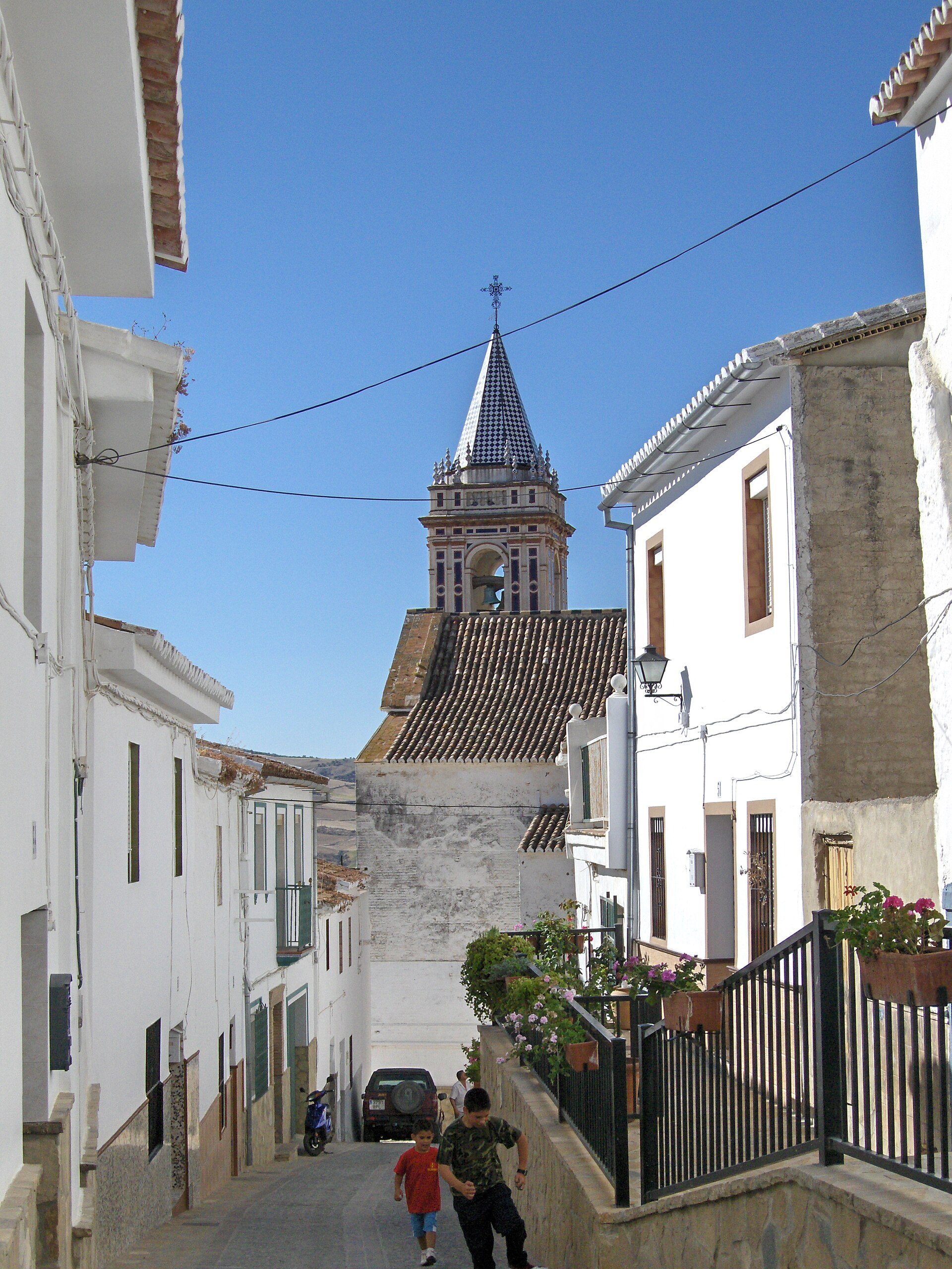 Traditional white-walled room with a view of a church tower and blue sky.