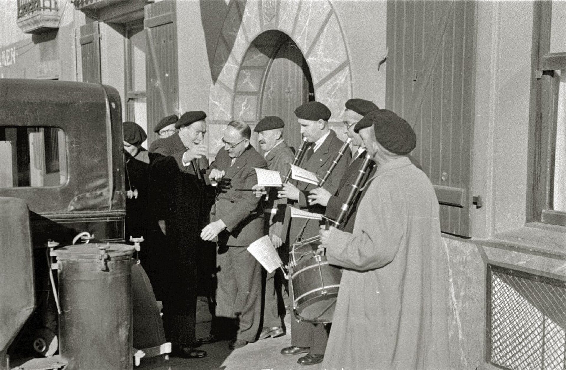 A group of musicians in a vintage setting, playing instruments and conversing.