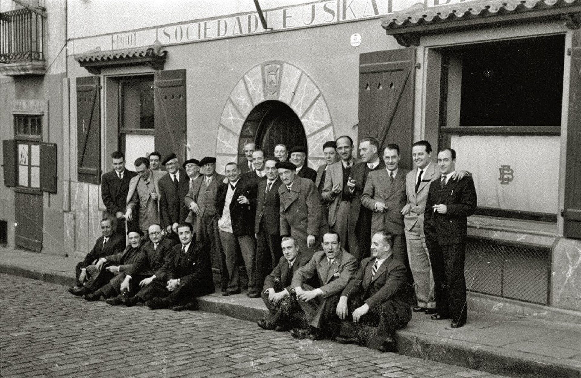 A group of people posing in front of a building with a large circular window.