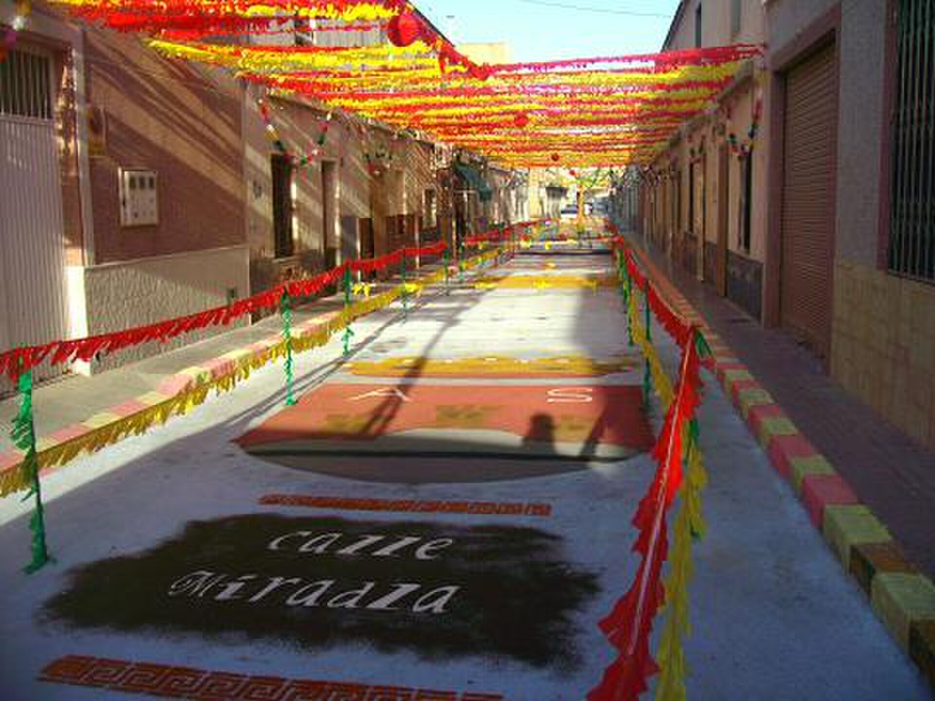 Colorful street with festive decorations and a "Calle Mirada" sign.