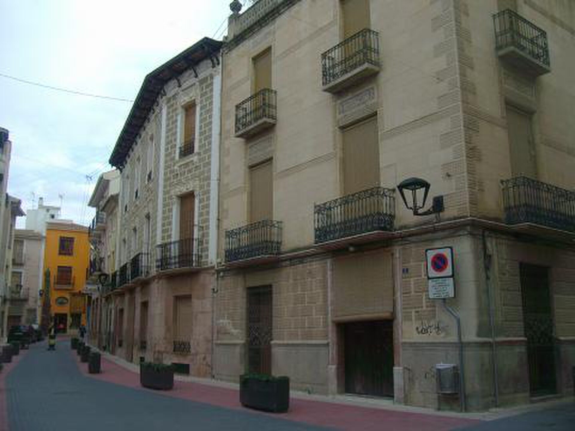 A street view of a European building with balconies, windows, and a street lamp.