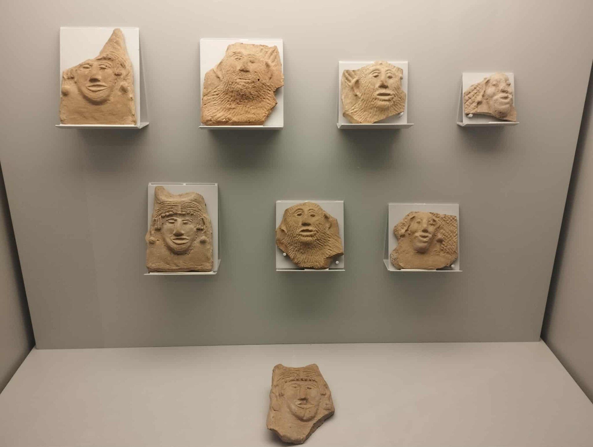 Alt text: Display of ancient stone masks in a museum exhibit.