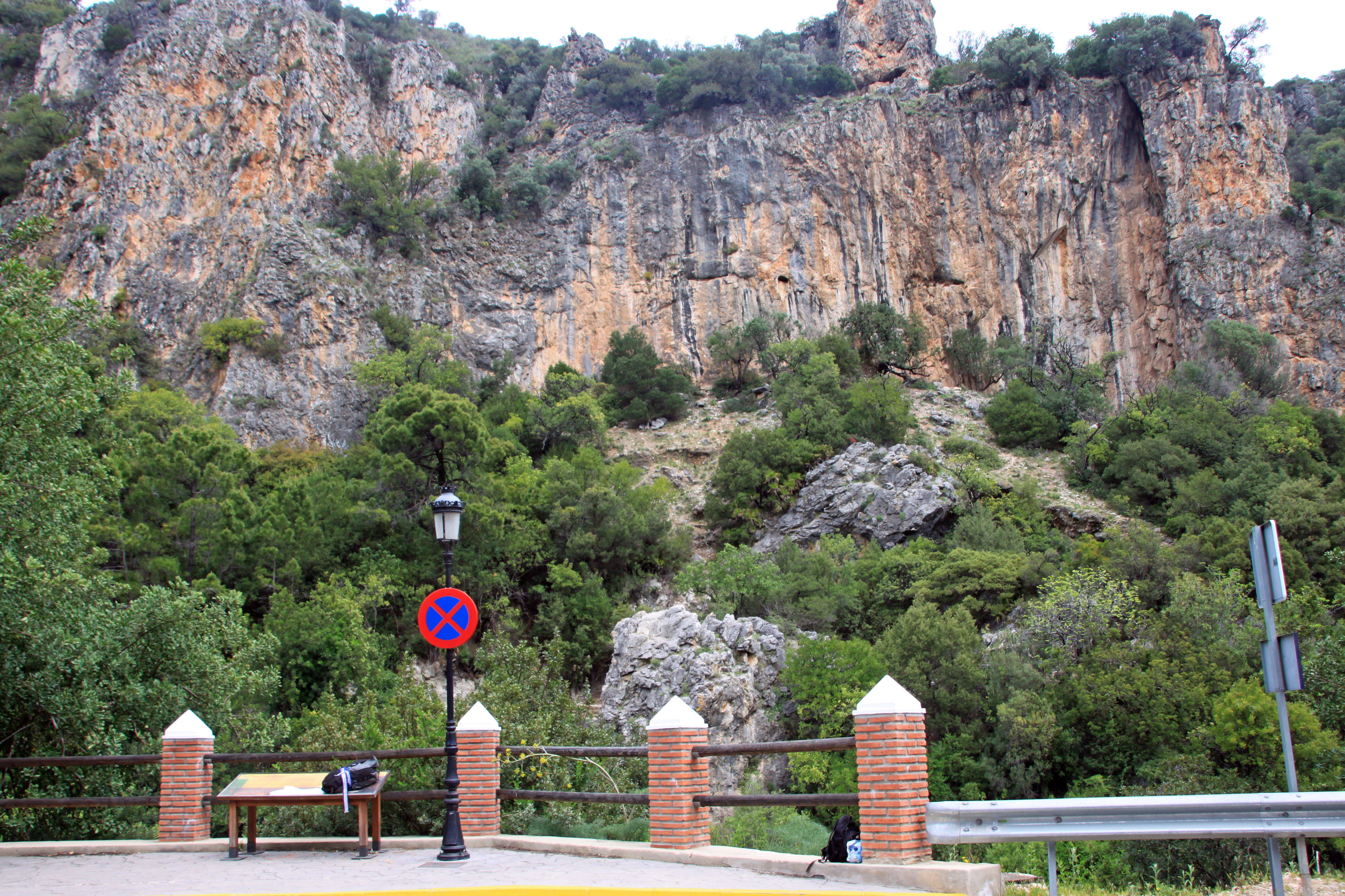 Rock formation view in Benahavís, Spain, featuring lush greenery and a parking sign.