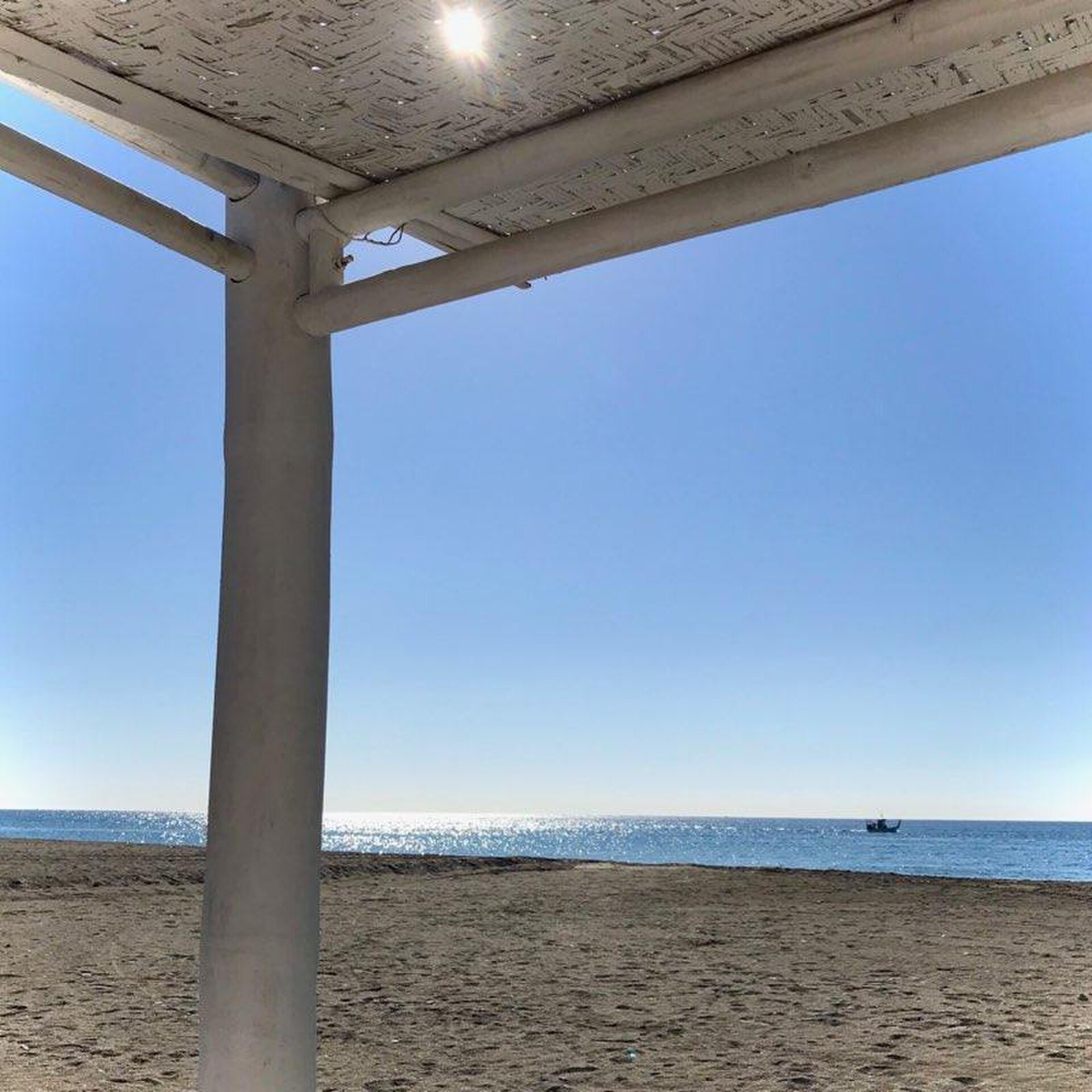 Beachfront view with clear blue sky, sandy beach, and ocean.