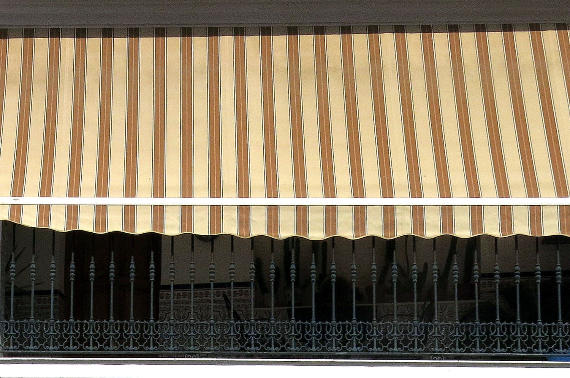 Striped awning over window with decorative metal grille.