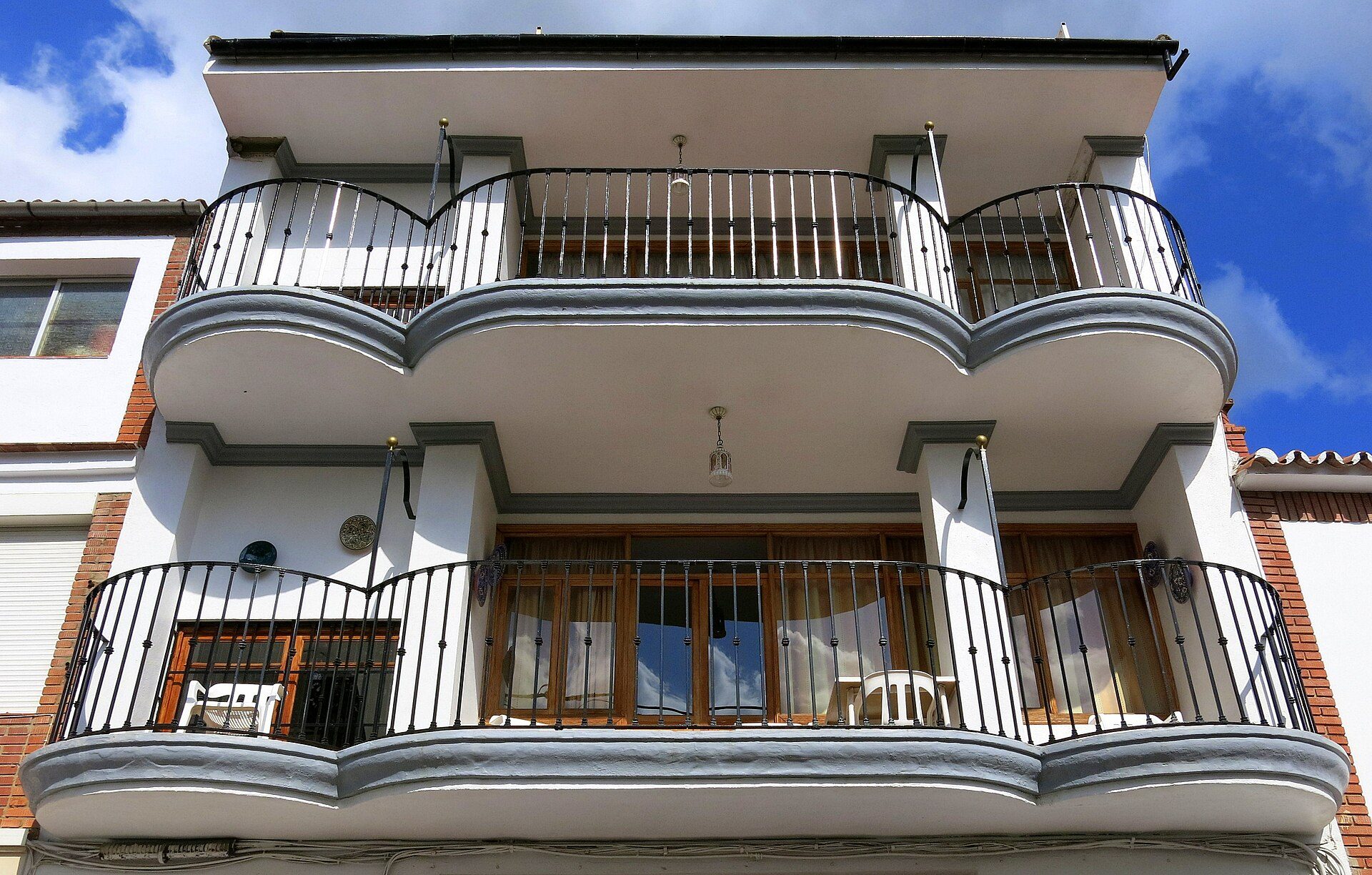 A modern apartment with a balcony, large windows, and a view of the sky.