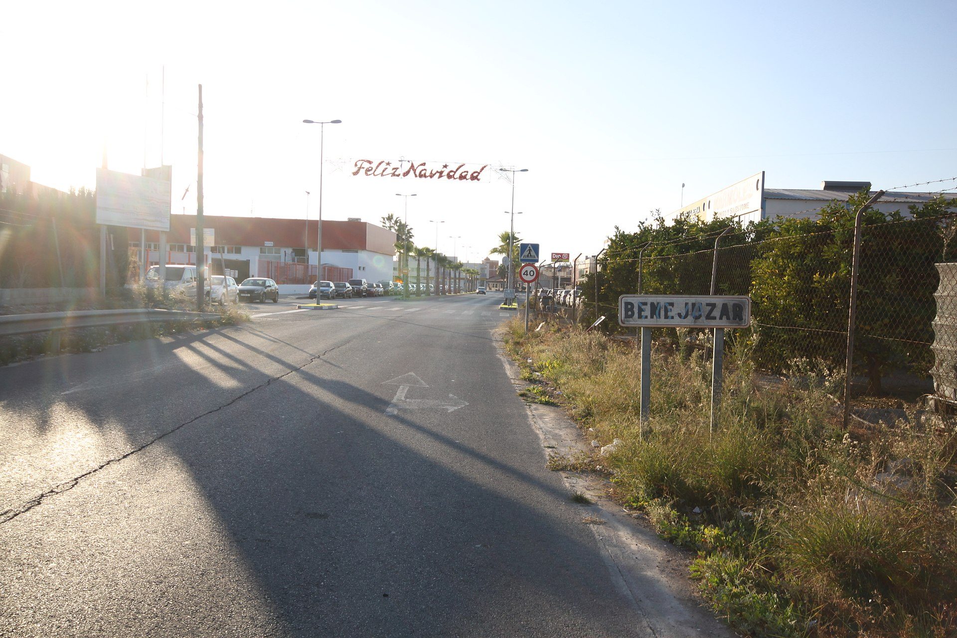 Alt text: "Empty street with a 'BENEFICIA JUZGAR' sign, sunlit with clear blue sky.
