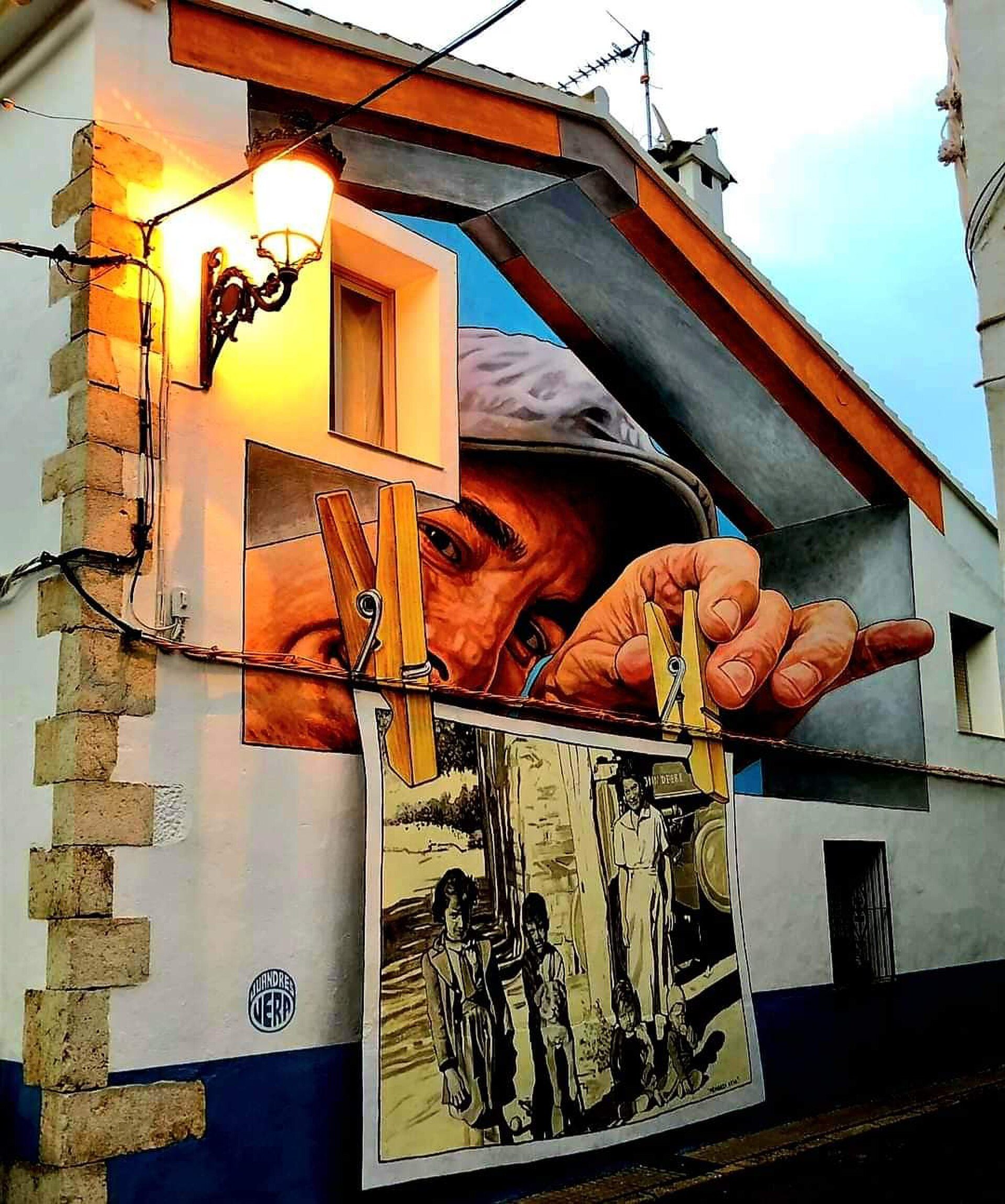 Mural of a man's face with a vintage train scene, hanging on a building wall.
