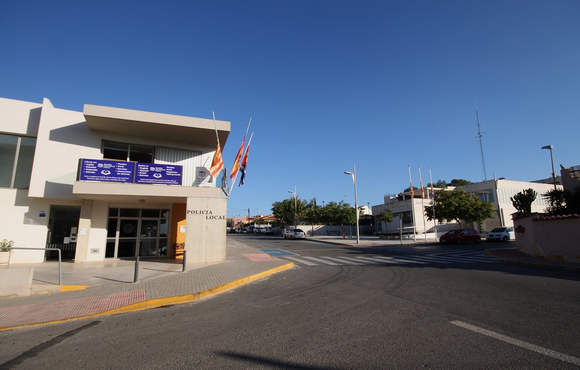 Modern building with flags, blue sky, and street view.