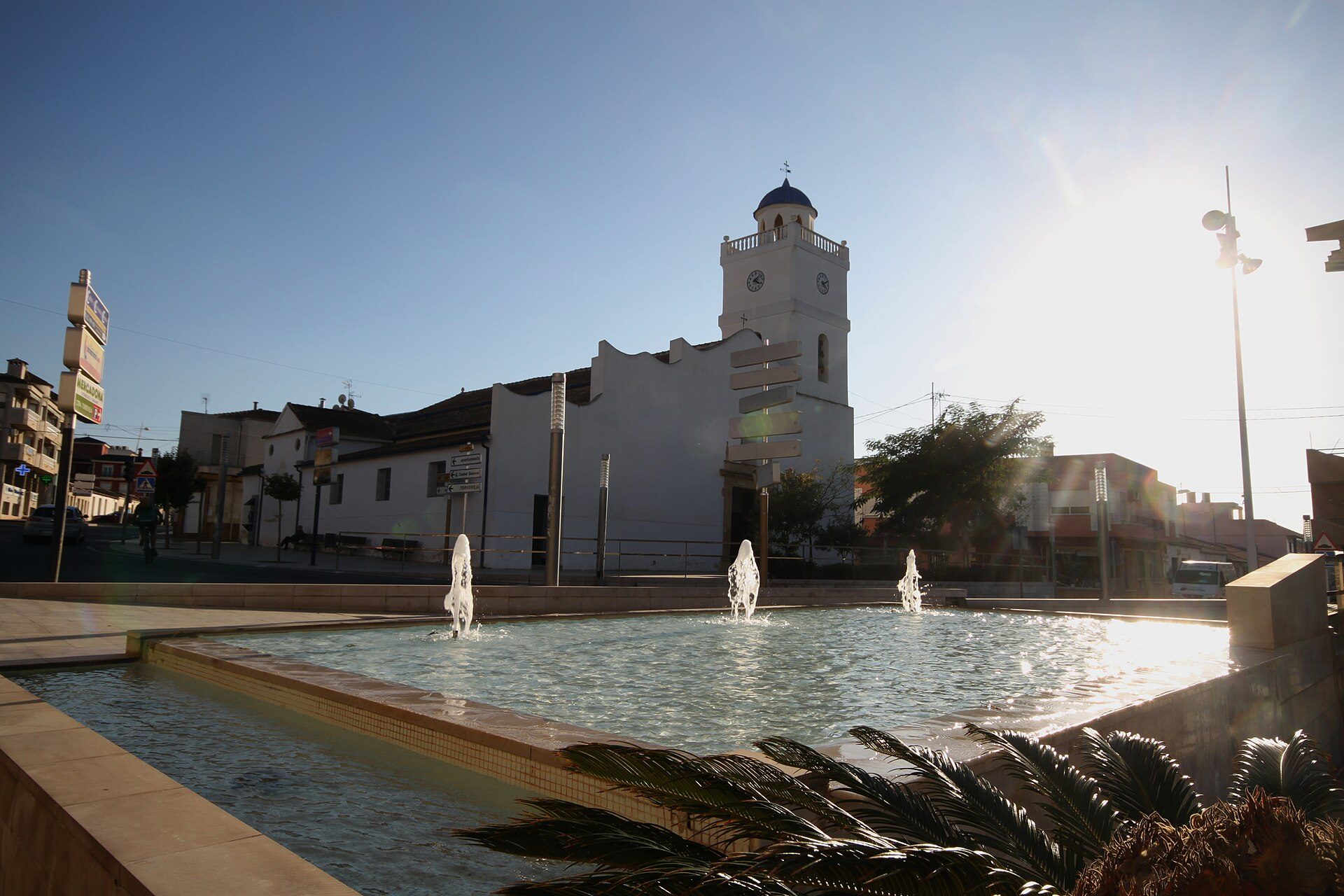 Alt text: Outdoor fountain with a church and clear blue sky in the background.
