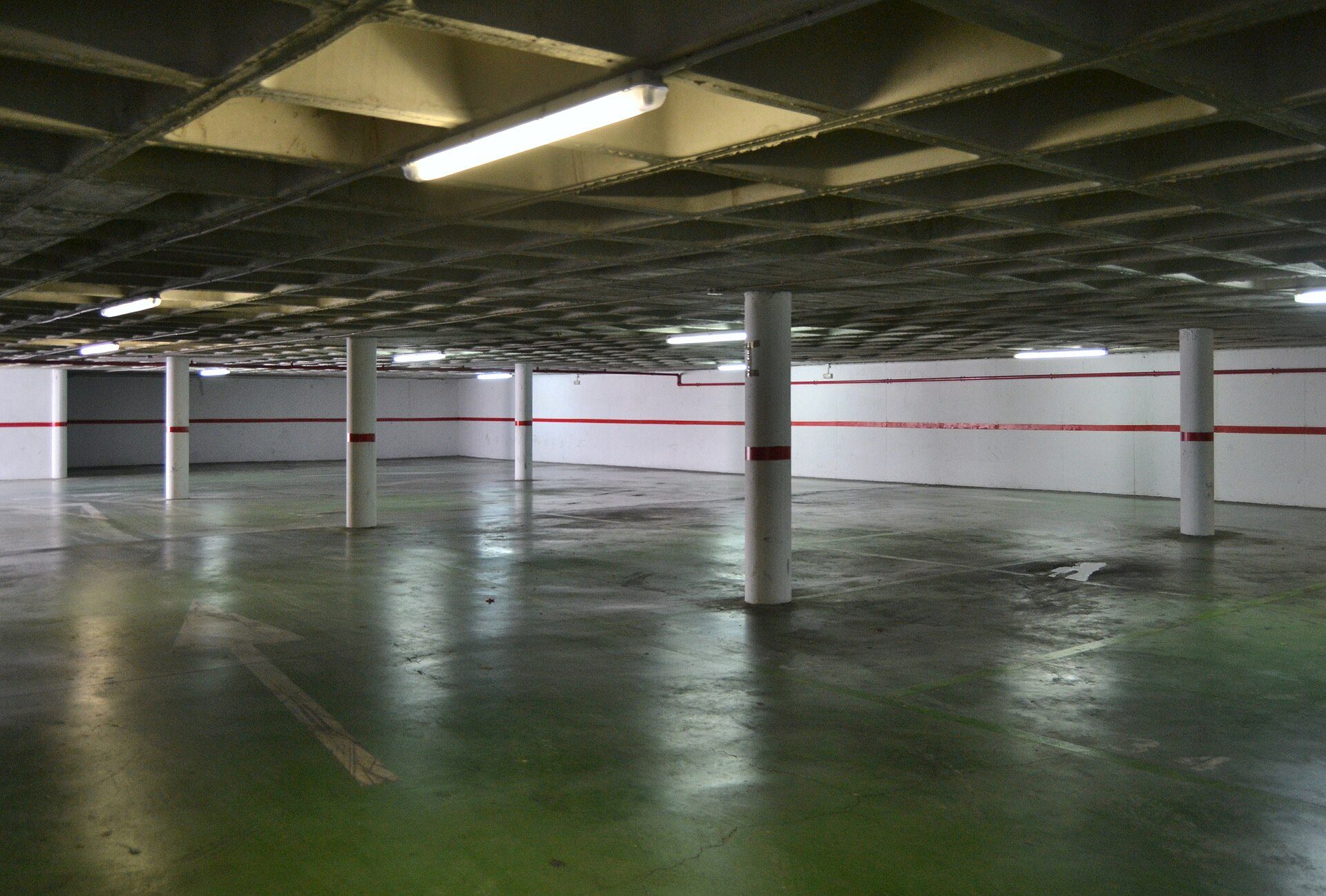 Industrial-style parking garage with concrete floors and white pillars.