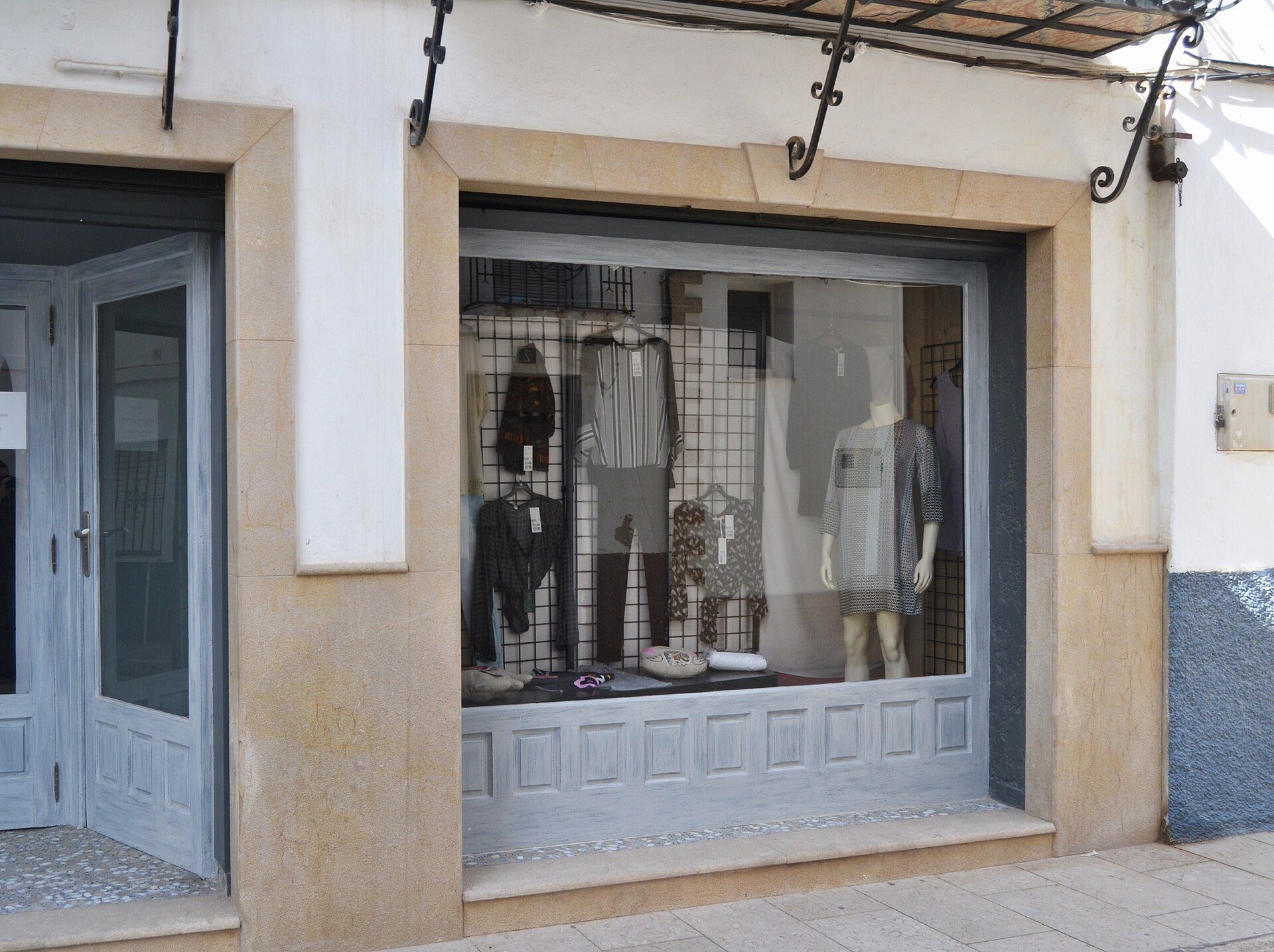 Storefront with clothing display, large windows, and decorative metal fixtures.