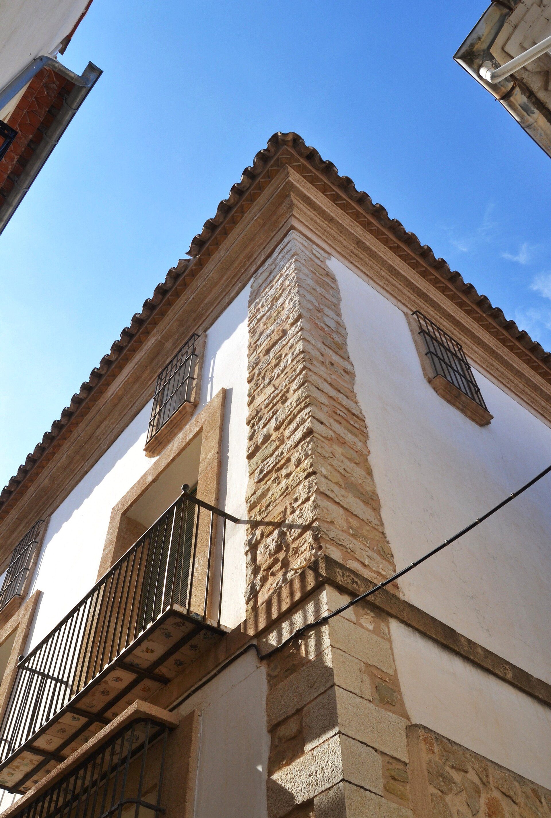 Traditional building with stone facade, white walls, and a balcony.