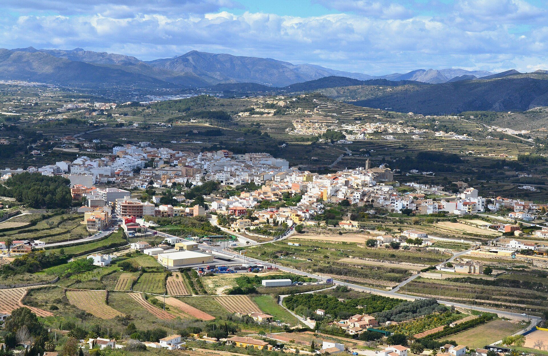 Alt text: Aerial view of a quaint village with terraced fields and distant mountains.