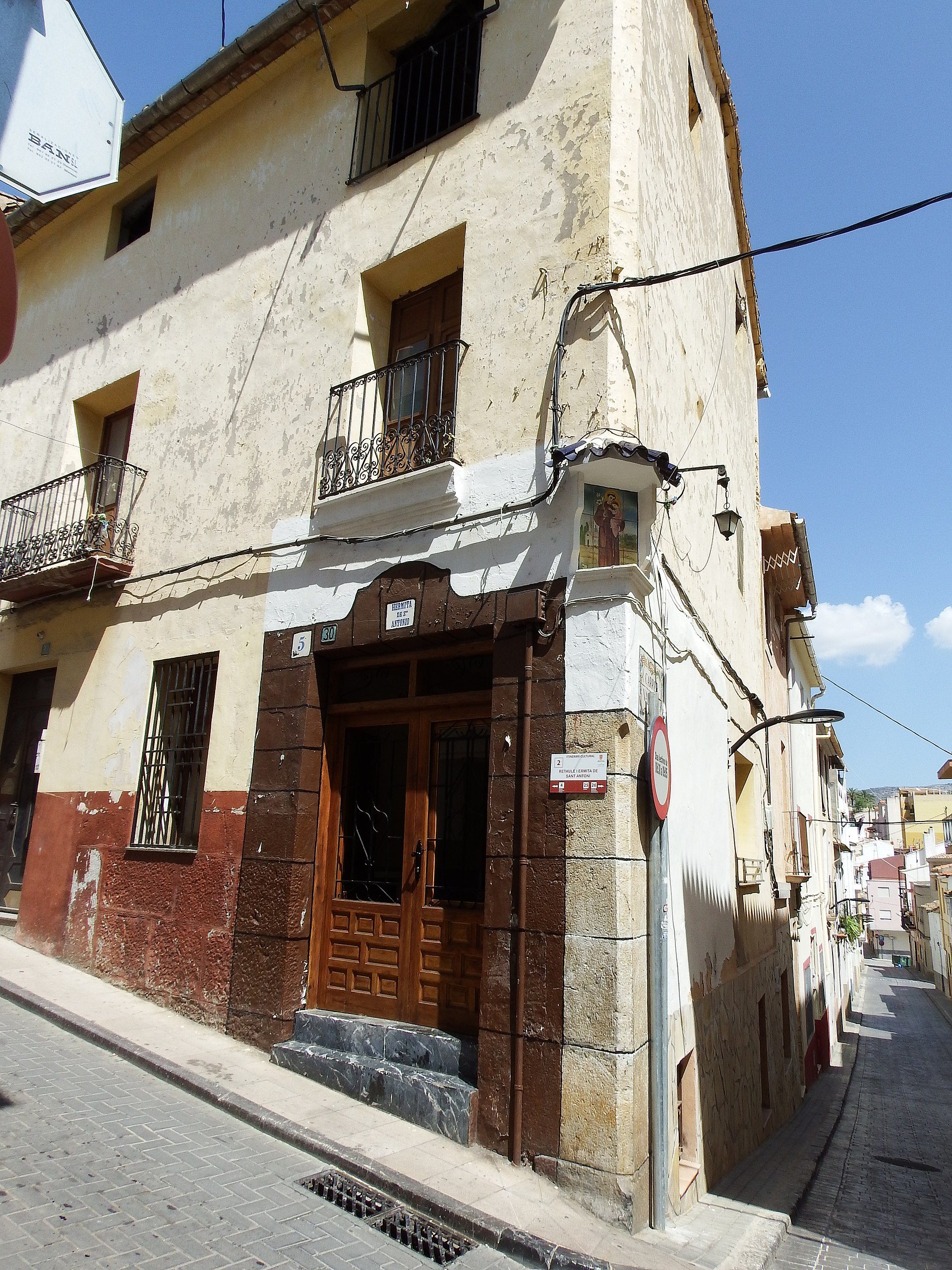 Traditional building with wooden doors, balconies, and a narrow street view.