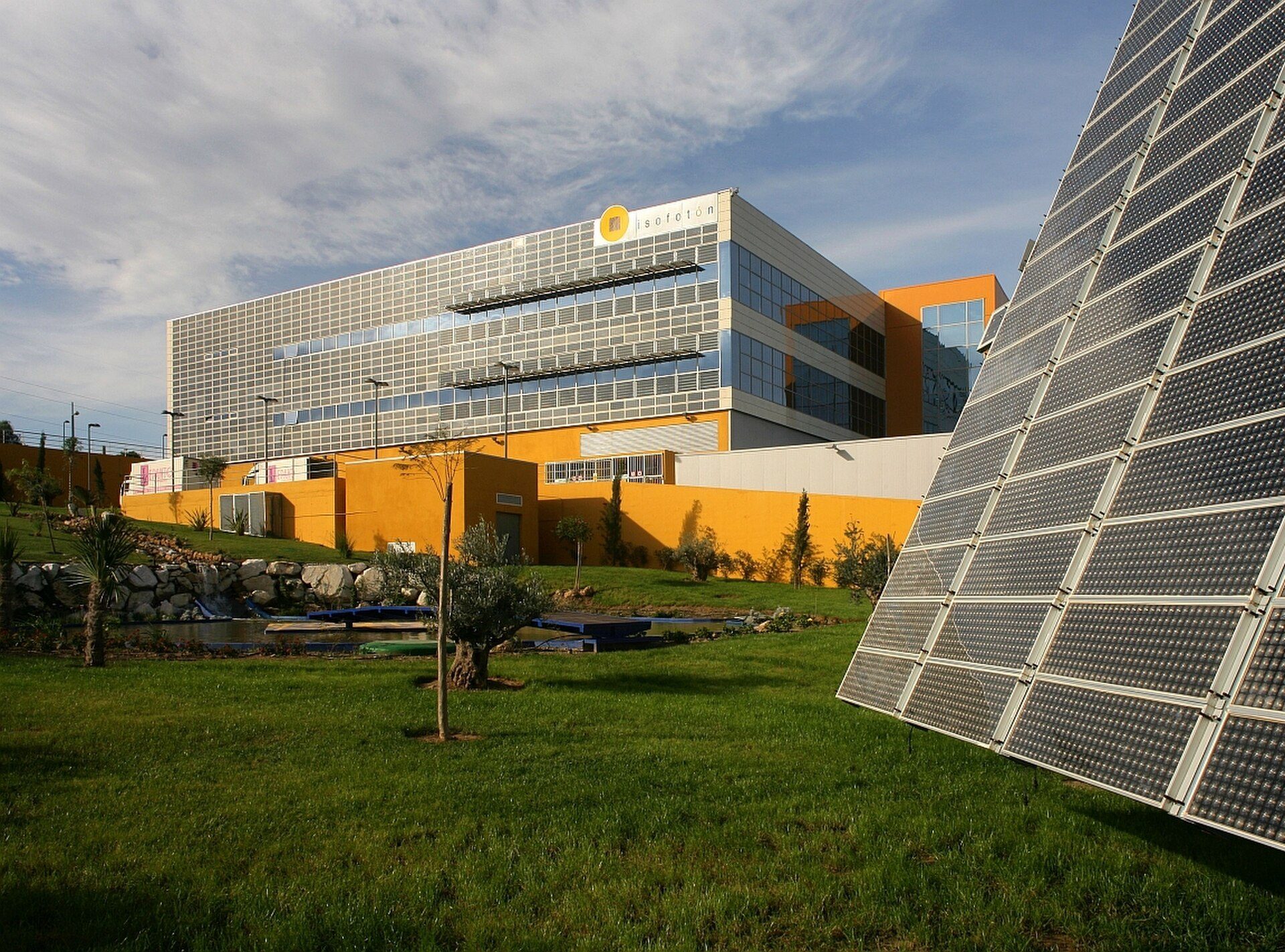Modern office building with solar panels, green lawn, and clear sky.