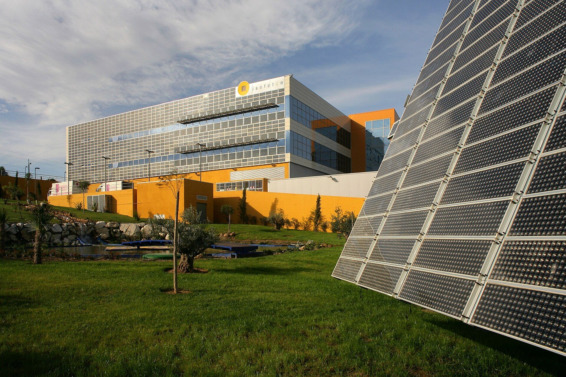 Modern office building with solar panels, large windows, and landscaped grounds.