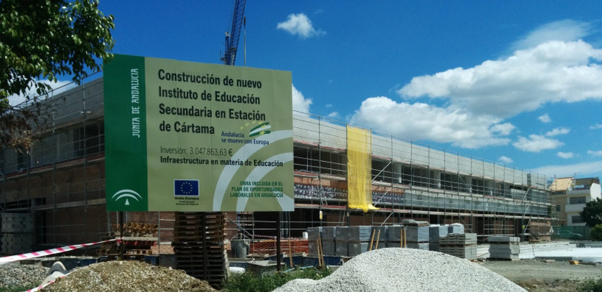 Construction site of a new education building with scaffolding and signage.