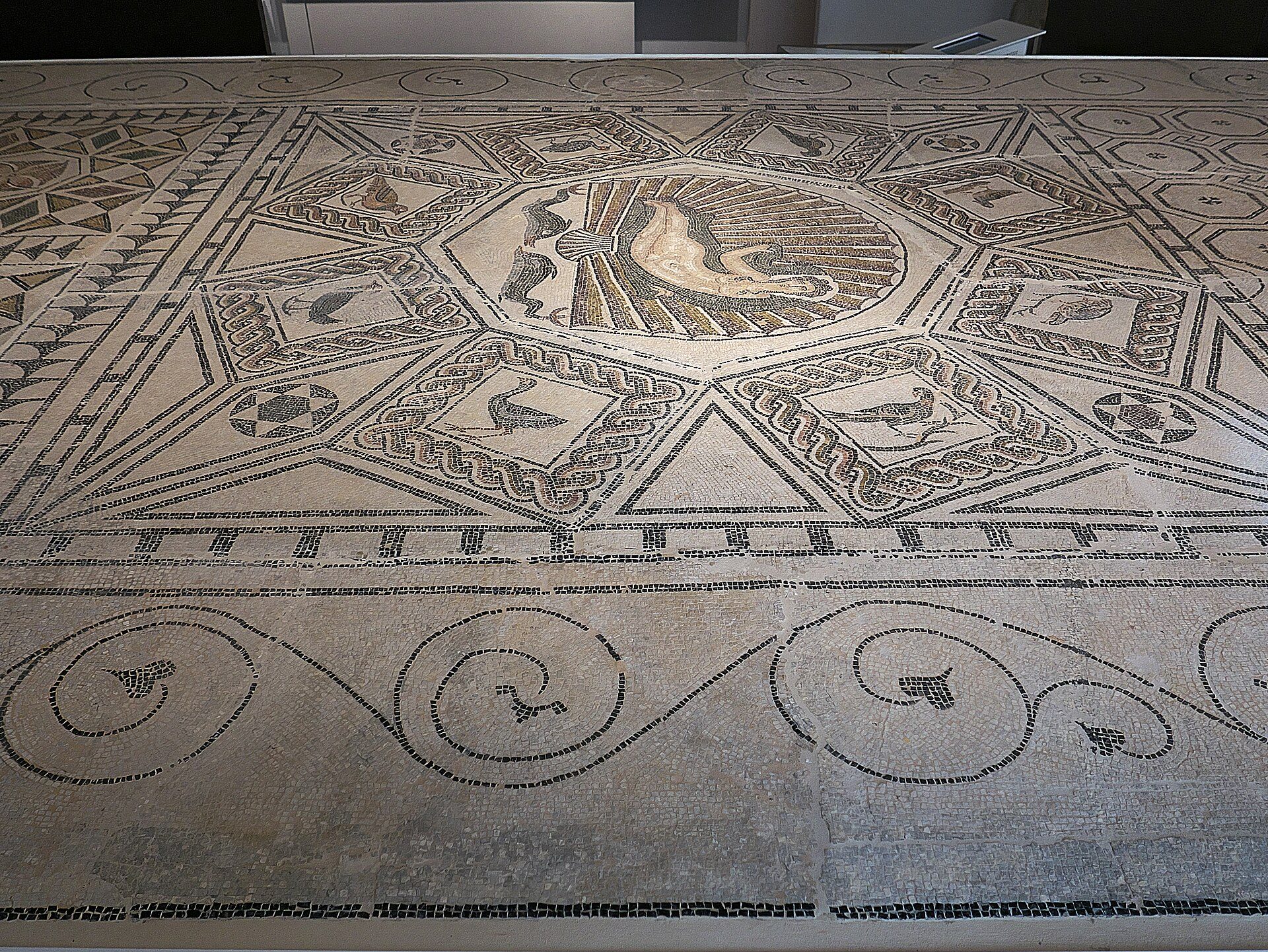 Alt text: Intricate mosaic floor with geometric patterns and central medallion in a room.