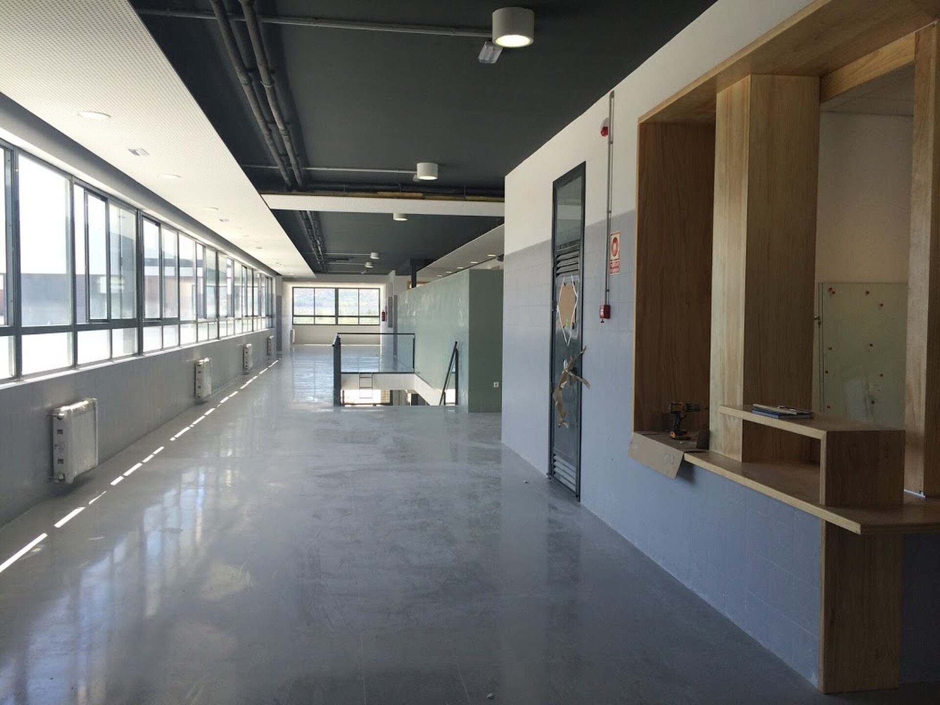 Industrial-style office space with large windows, concrete floor, and wooden accents.
