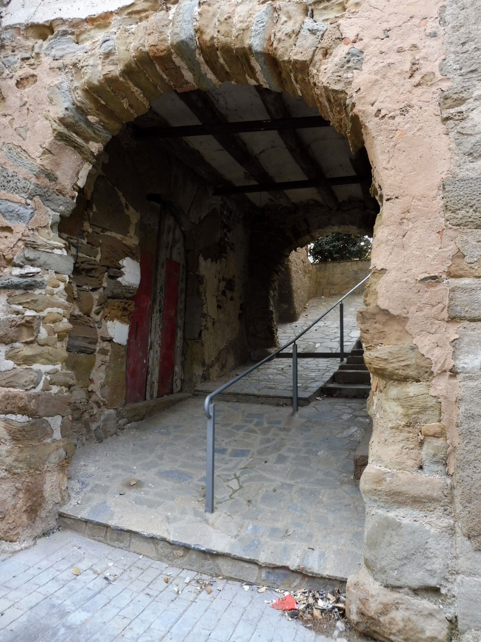 Old stone archway leading to a narrow staircase with metal railing.