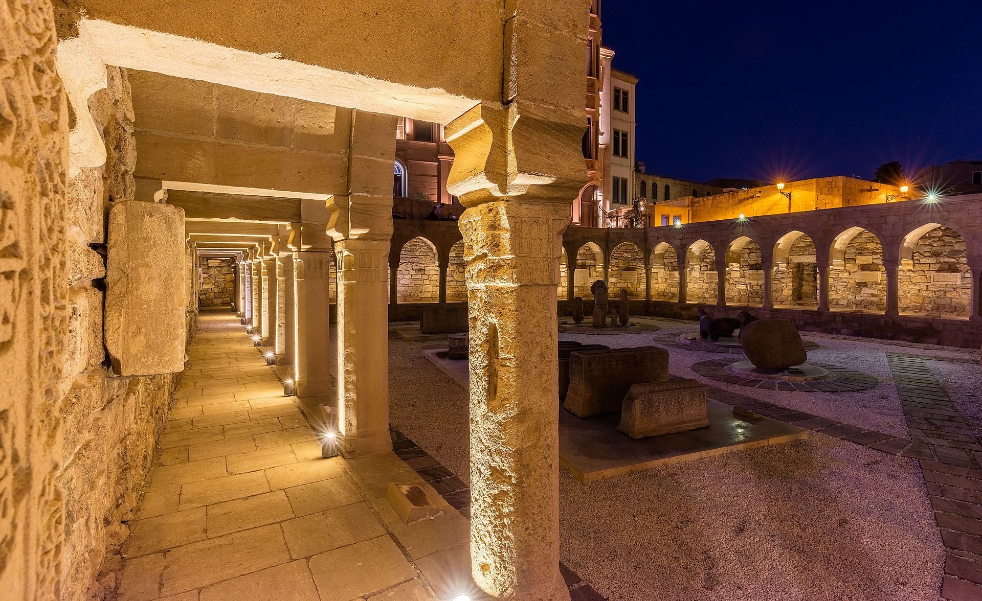 Alt text: Historic courtyard with stone columns, arches, and ambient lighting at night.