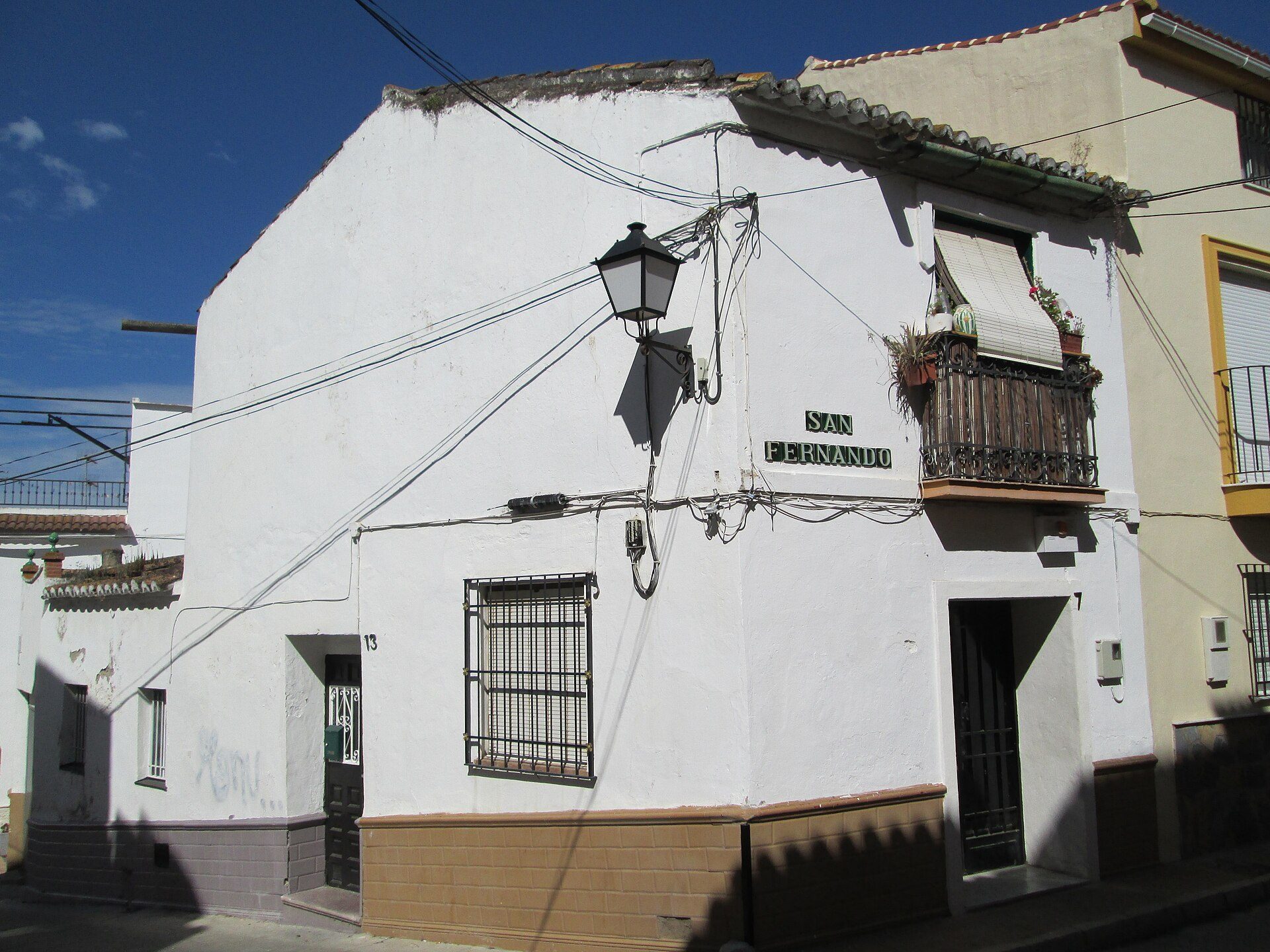 White two-story building with a balcony, street view, and multiple windows.