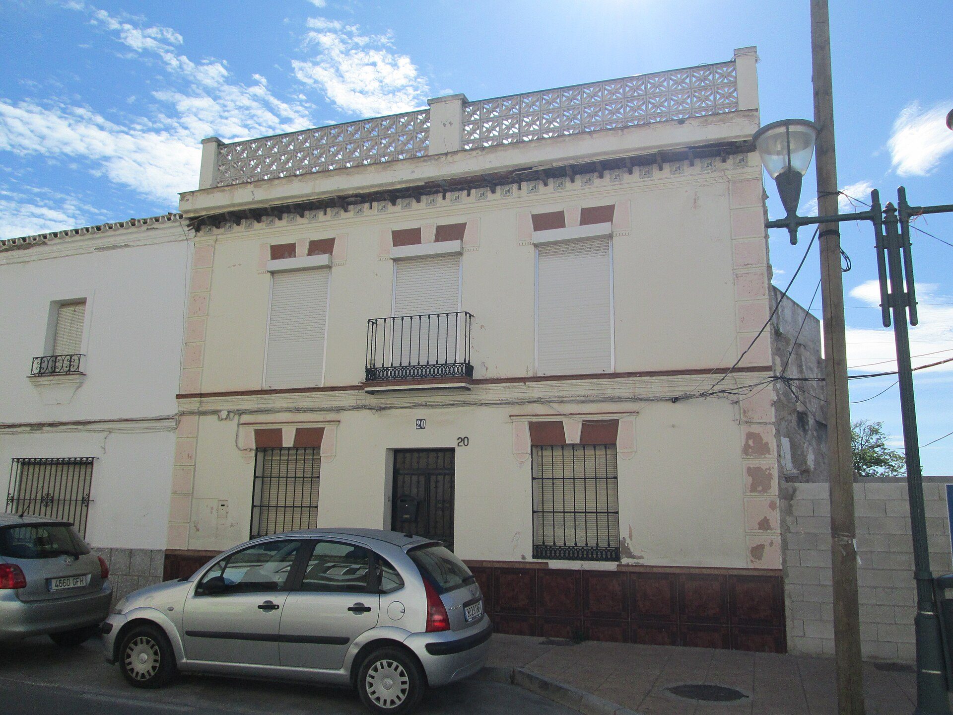 Two-story building with a balcony, white shutters, and a street view.