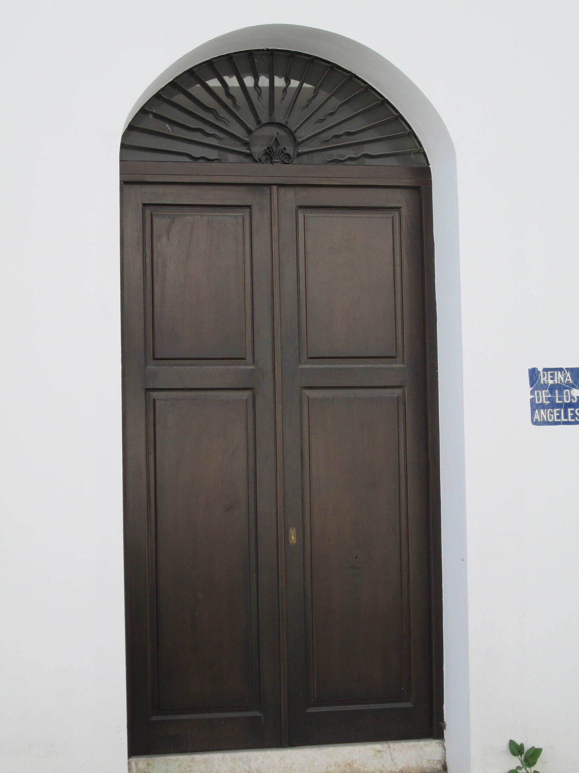 Alt text: "Dark wooden double doors with an arched transom window above.