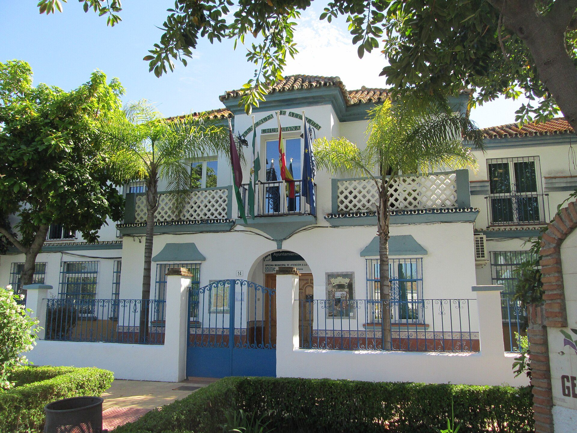 Two-story building with balconies, lush greenery, and a courtyard.