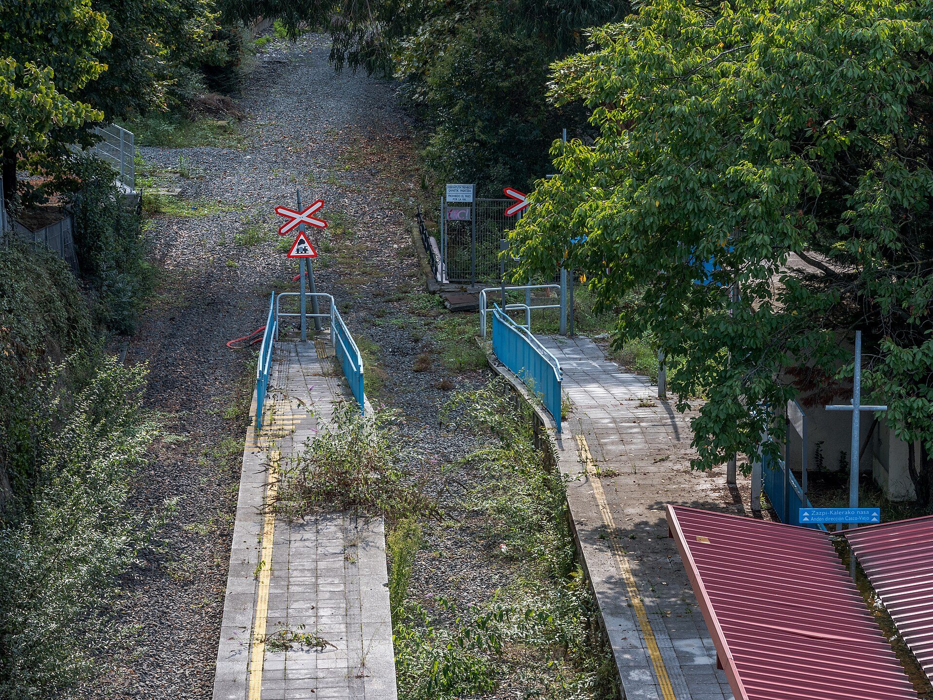 Alt text: Outdoor area with a gravel path, blue railings, and greenery.