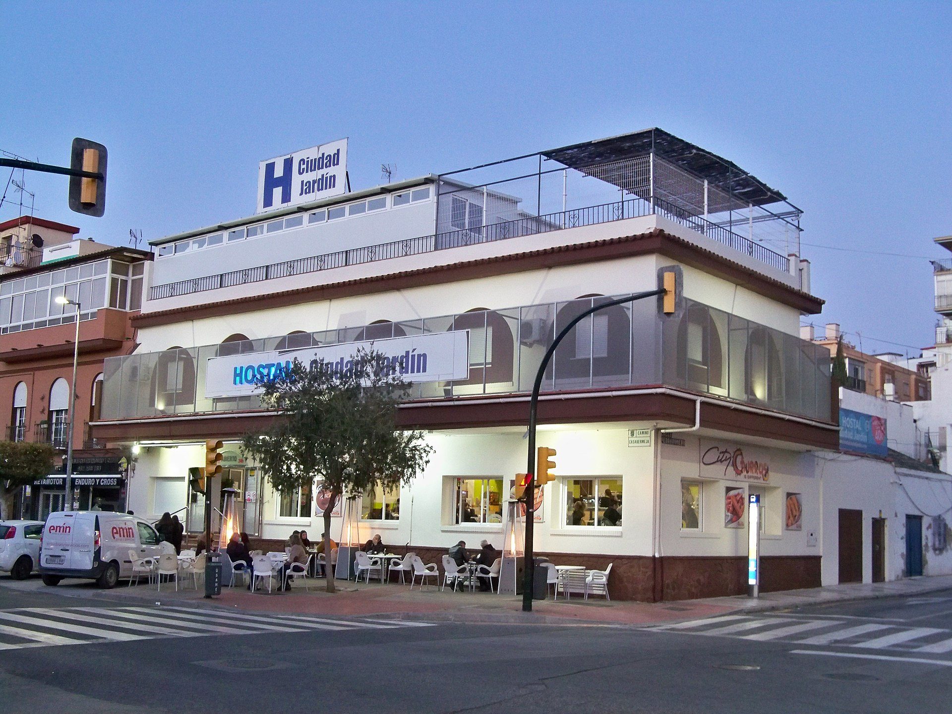 A modern hotel with a rooftop terrace, featuring a restaurant and outdoor seating.