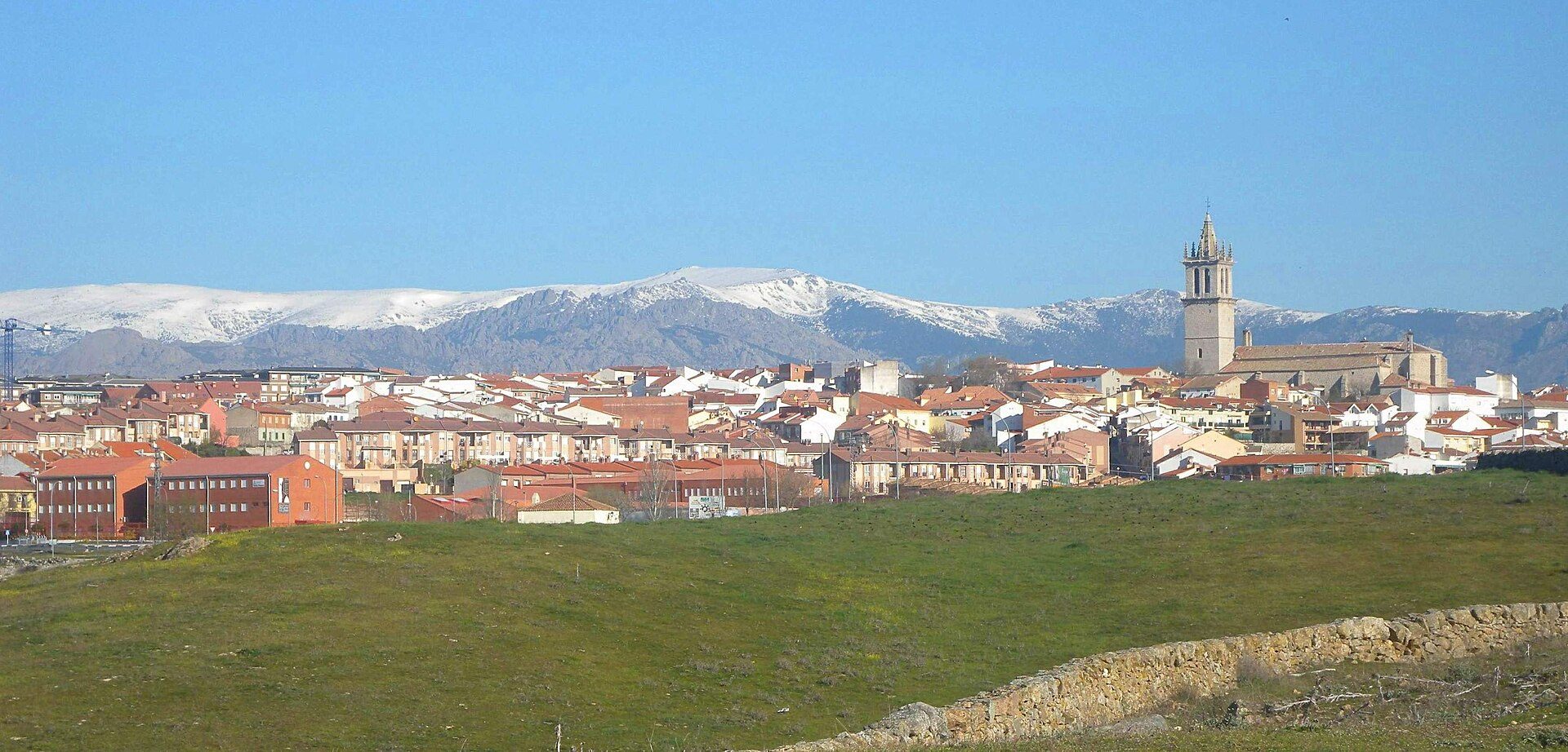 Alt text: Panoramic view of a snowy town with a church tower and mountains in the background.