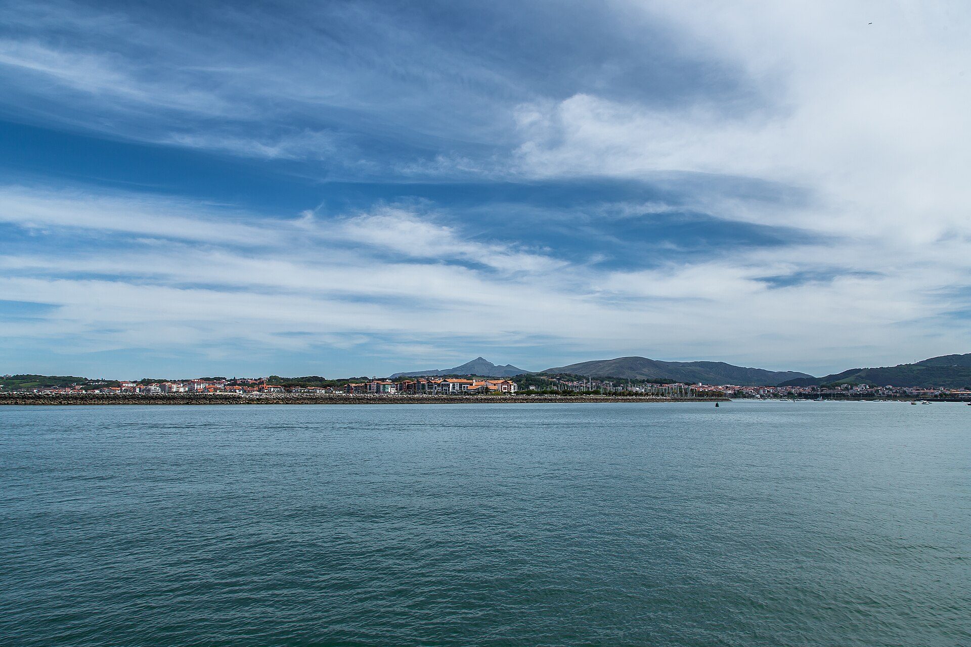Coastal view from a spacious room with large windows and a balcony.